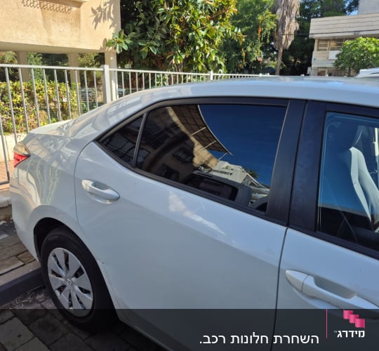 רכב עם חלונות כהים חונה ליד גדר